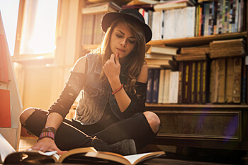 junge Frau sitzt grübelnd vor Büchern