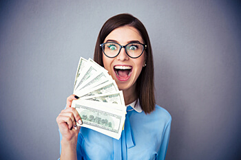 junge Frau zeigt lächelnd viele Geldscheine