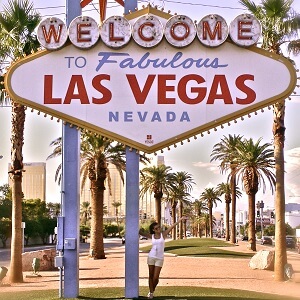 Tourismus Studentin der ISM posiert unter Las Vegas Schild zwischen Palmen